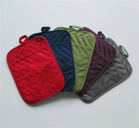 Pot holders with pockets - Use the Kitchen Aid Asteroid Pot Holders 2 Pack to protect hands from the heat when handling hot pots, pans, and dishes. These oval pot holders each measure 6.5 in. wide by 10 in. long and feature a slide pocket for your hand for easy on and off use while youftre cooking and baking.
